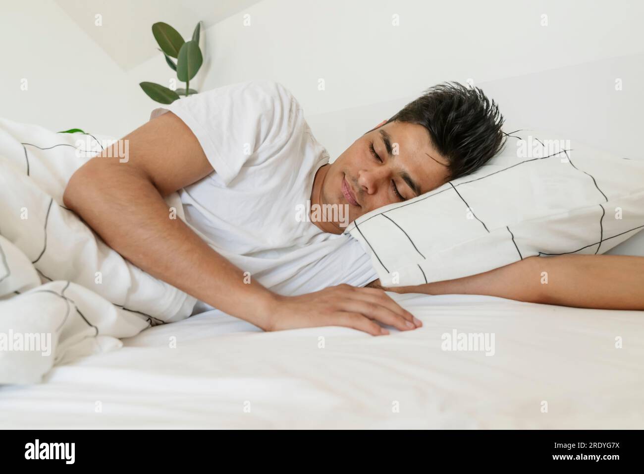 Ein junger Mann schläft zu Hause im Bett Stockfoto