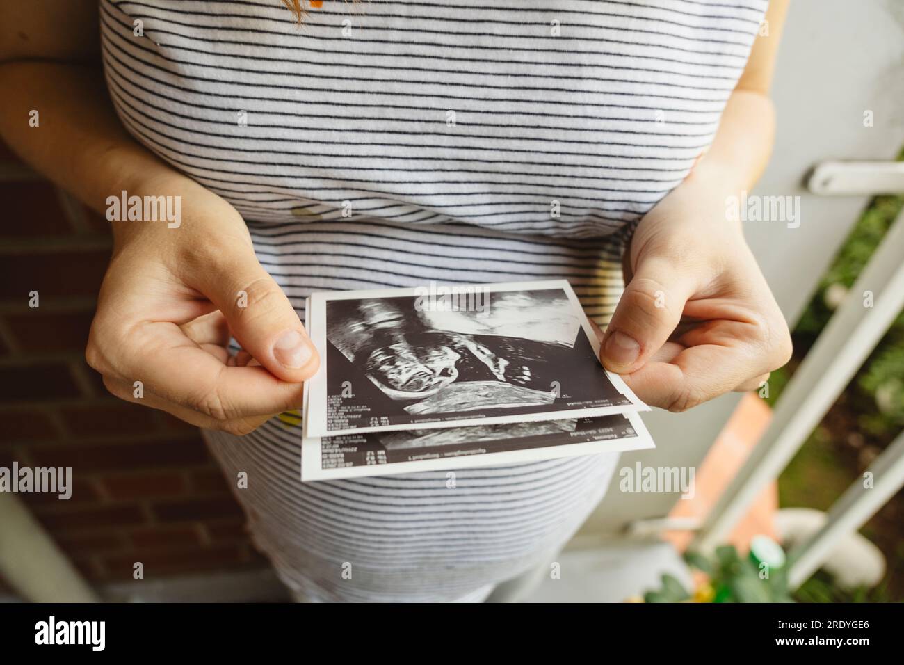 Schwangere Frau, die zu Hause ein Ultraschallbild hält Stockfoto