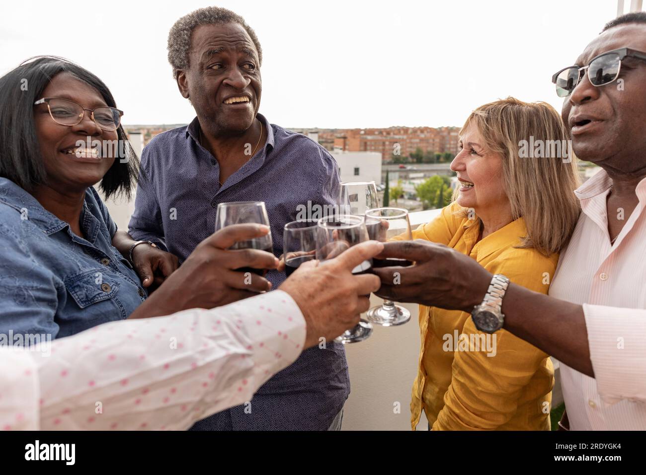 Glückliche Freunde, die auf dem Balkon Getränke toasten Stockfoto