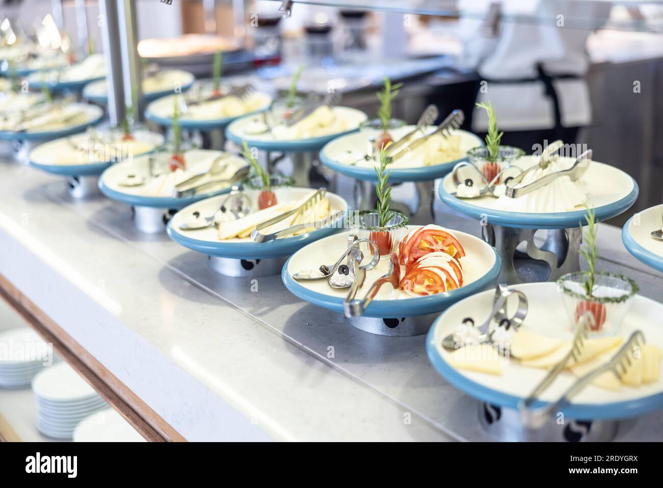 Gestalten Sie den Büfetttisch im Hotelrestaurant kreativ. Tomaten mit Mozzarella und Oliven auf einem Teller, sie führte andere Teller mit Käse und Kräutern. Stockfoto