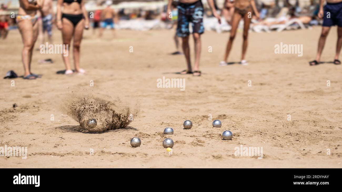 Petanque-Bälle im Sand am Meer während eines Spiels am Strand. Stockfoto