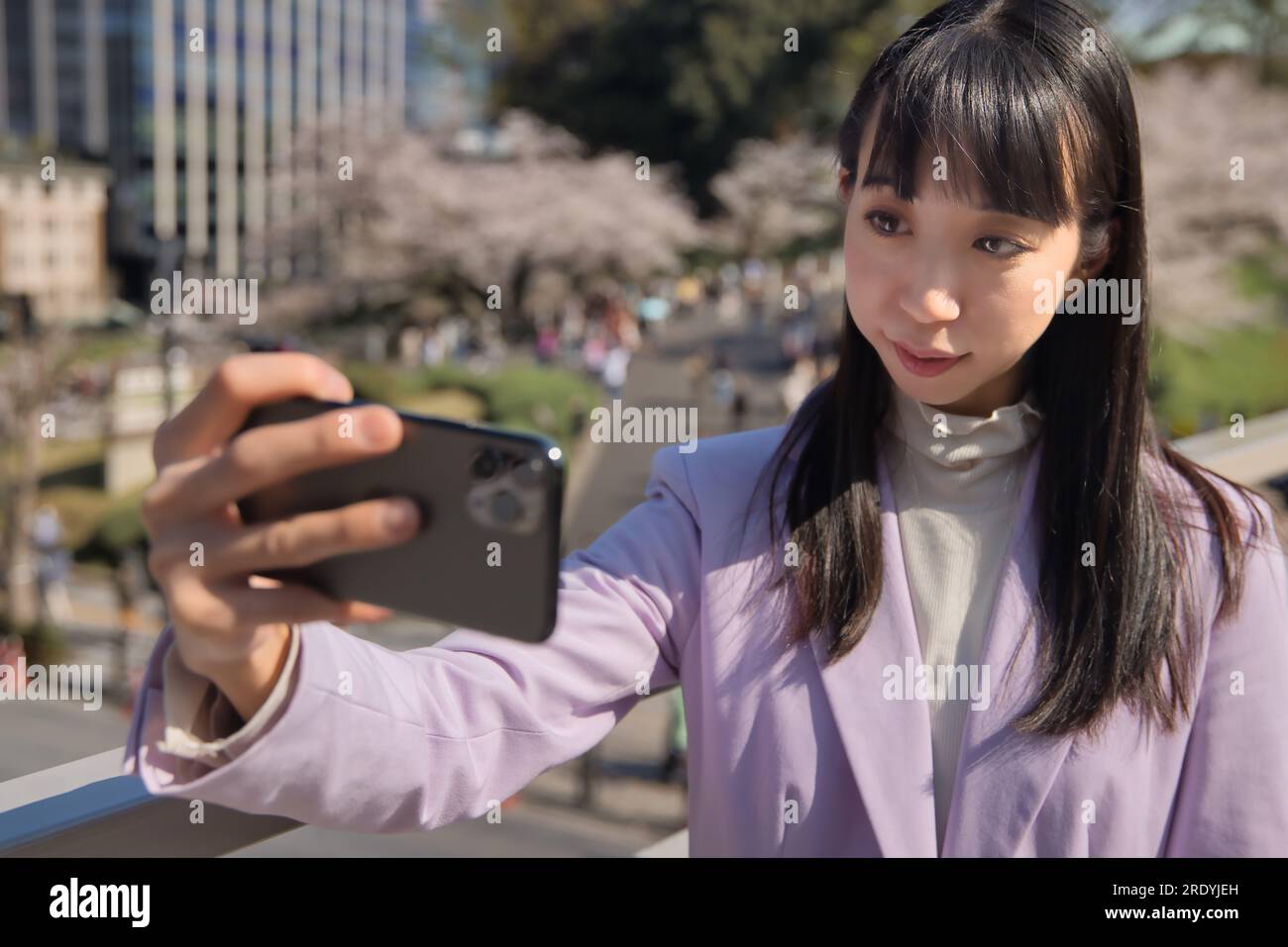 Ein Porträt des Selfie einer Japanerin hinter dem Kirschblütenabdruck Stockfoto