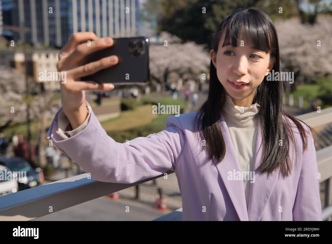 Ein Porträt des Selfie einer Japanerin hinter dem Kirschblütenabdruck Stockfoto