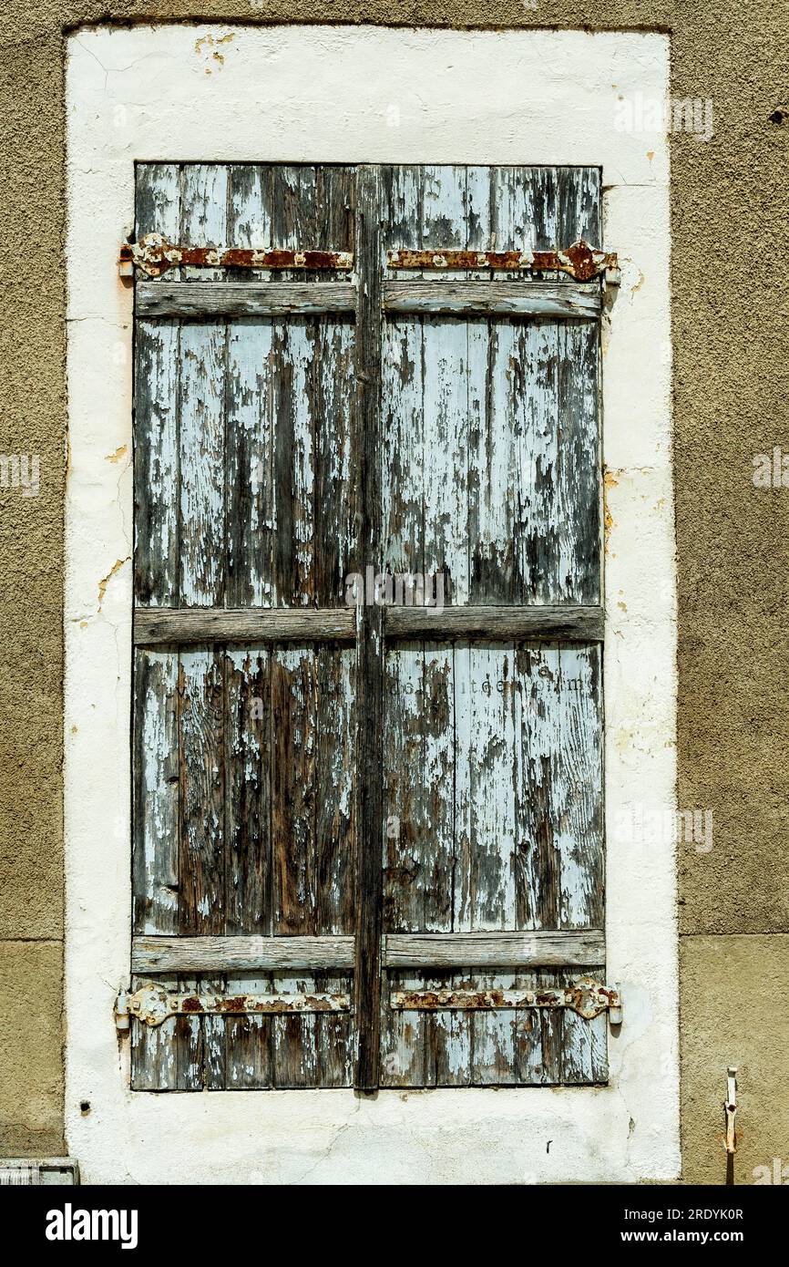 Verwitterte blaue Fensterläden in einem rustikalen Gebäude in einer ruhigen ländlichen Umgebung Stockfoto