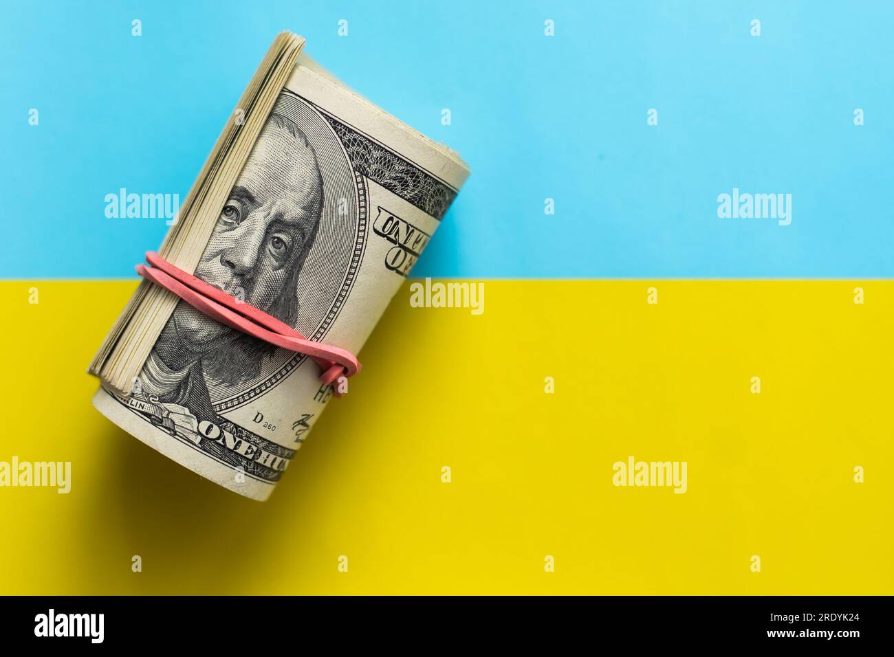 Dollar vor dem Hintergrund der ukrainischen Flagge. Krieg in der Ukraine. Finanzielle Hilfe und Unterstützung aus der ganzen Welt. Investitionen im Land. Ausleihen Stockfoto