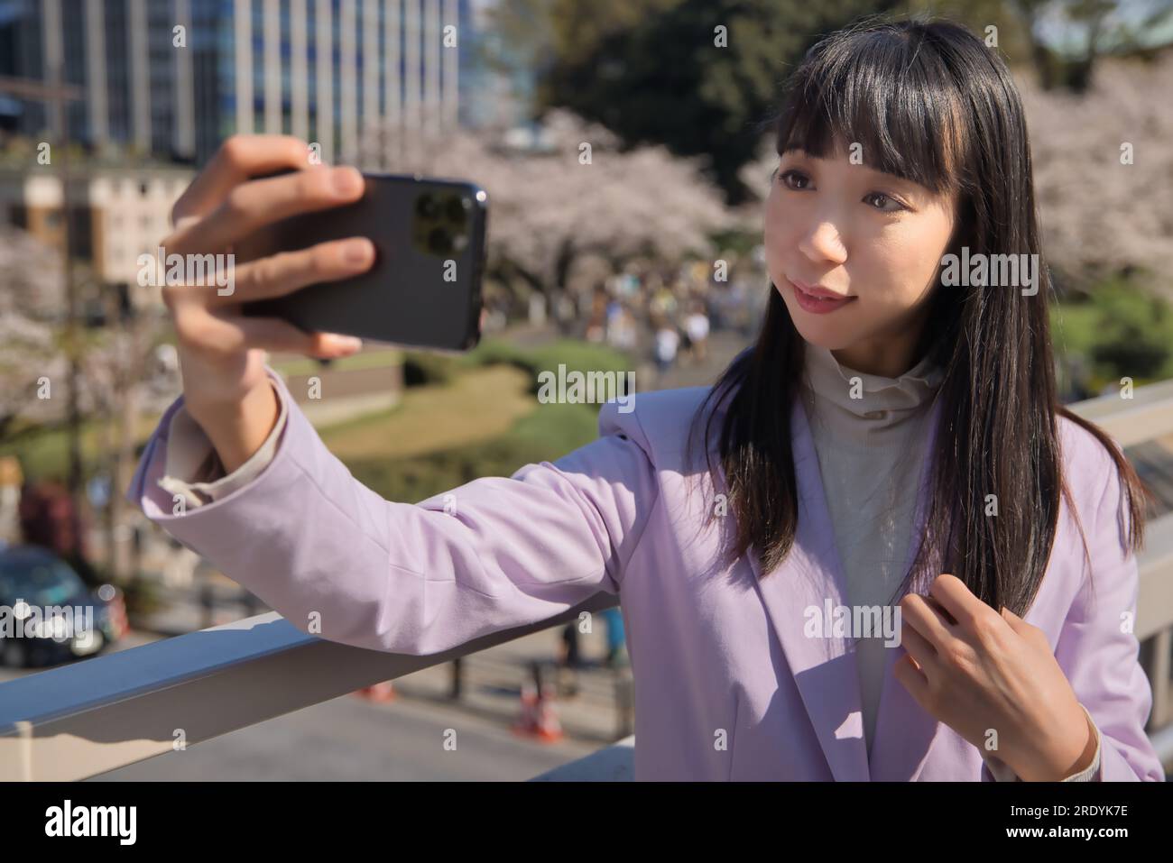 Ein Porträt des Selfie einer Japanerin hinter dem Kirschblütenabdruck Stockfoto