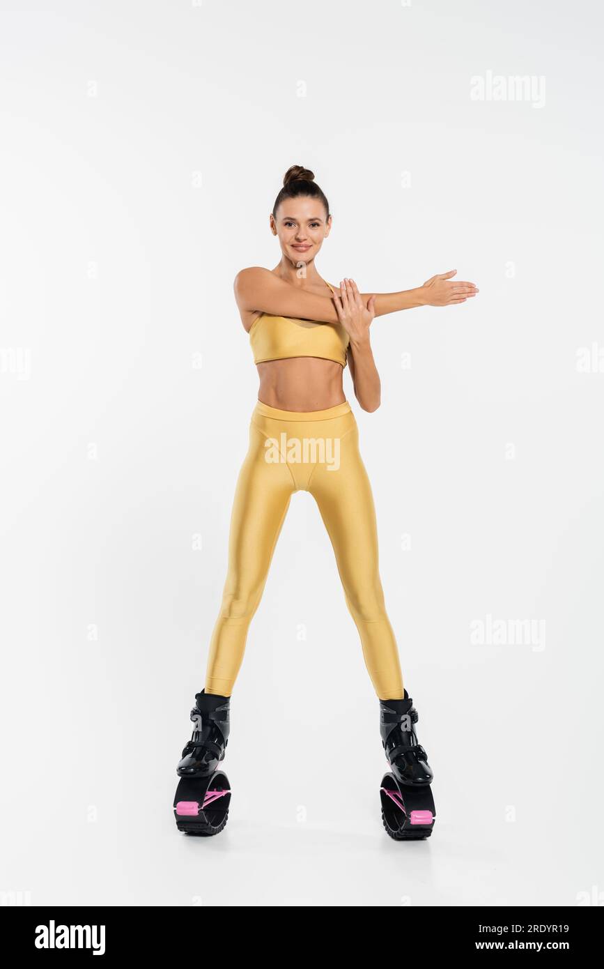 Fröhliche Frau in Fitnesskleidung und kangoo-Sprungschuhen, weißer Hintergrund, Energie Stockfoto