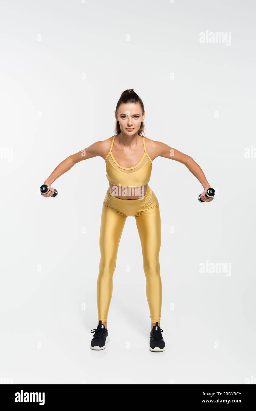 Fit Sportlerin in Fitnesskleidung Training mit Kurzhanteln auf weißem Hintergrund, Fitnessmotivation Stockfoto