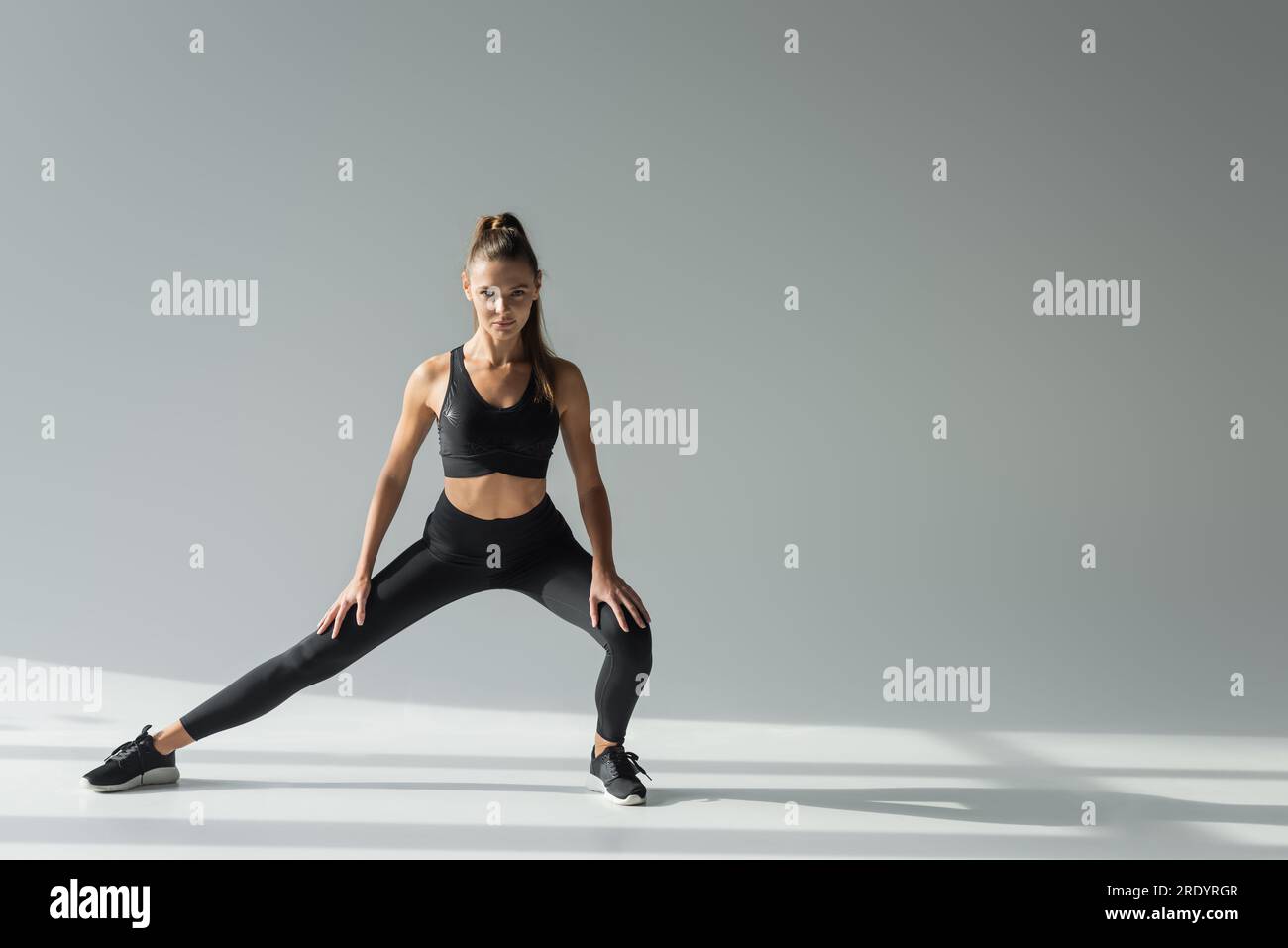 Workout, Sportlerin mit körperbetontem Training auf grauem Hintergrund, sportliches Outfit Stockfoto
