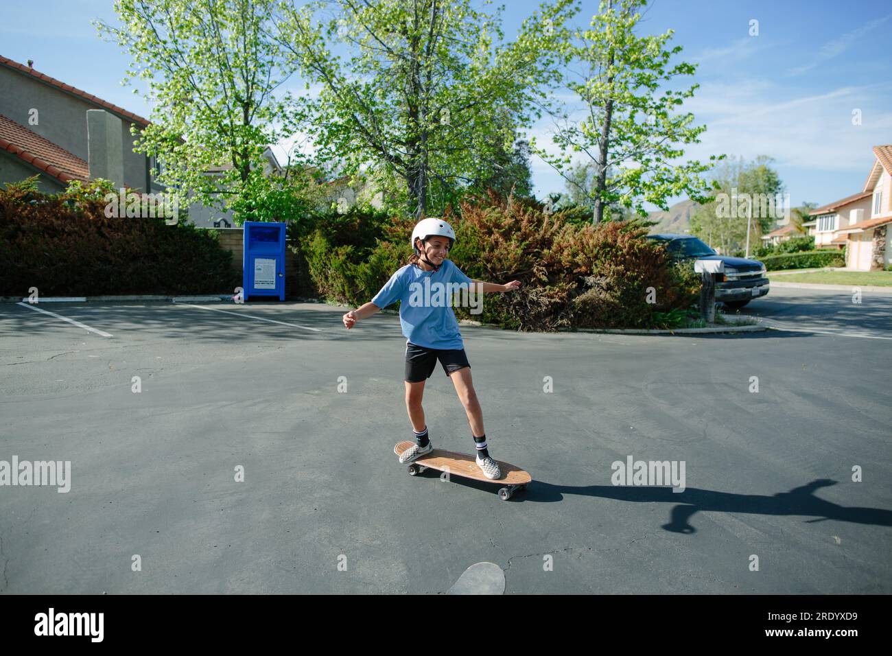 Ein Mädchen, das auf einem leeren Parkplatz Skateboard fährt Stockfoto