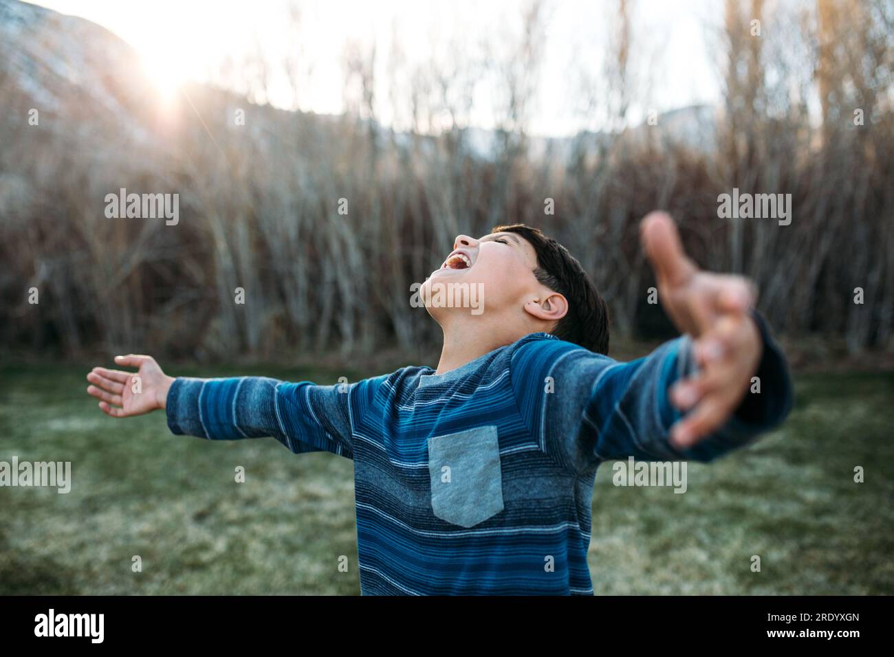 Ein Junge mit breiten Armen schreit fröhlich zum Himmel Stockfoto