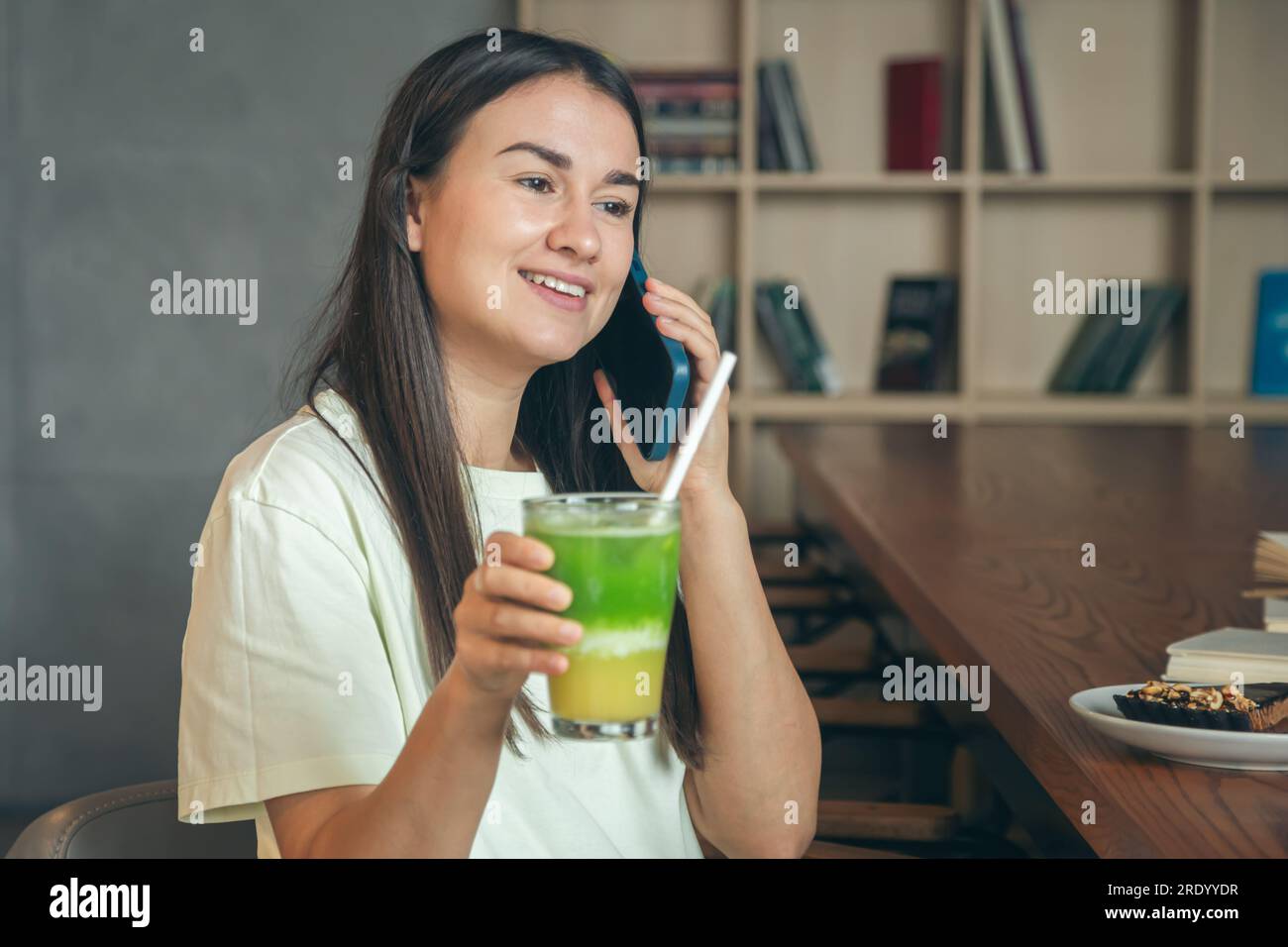 Eine Frau in einem Café mit einem Smartphone und einem Glas Limonade. Stockfoto