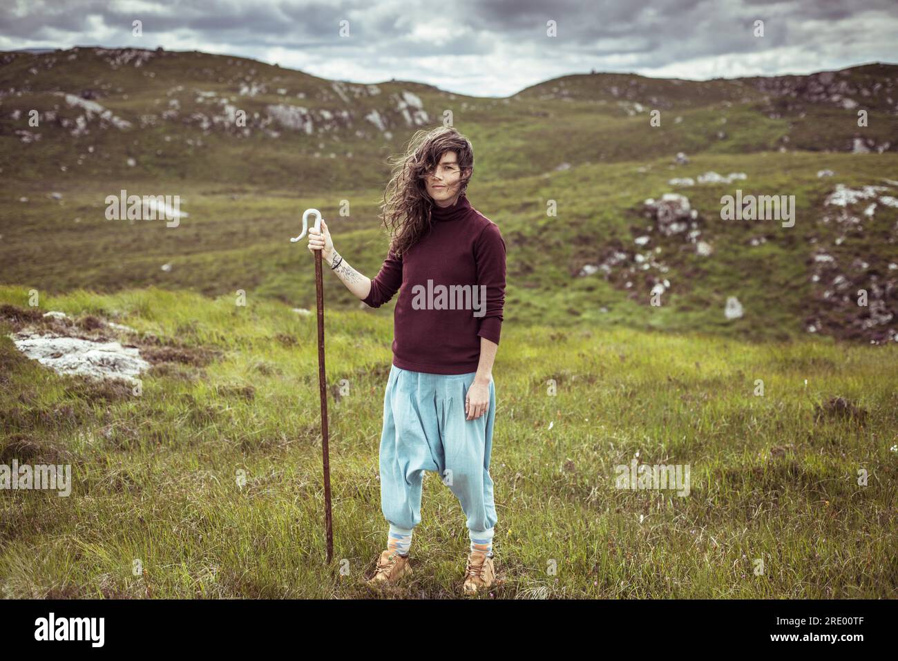 Porträt einer wilden Frau mit Personal in abgelegenen Bergen Stockfoto
