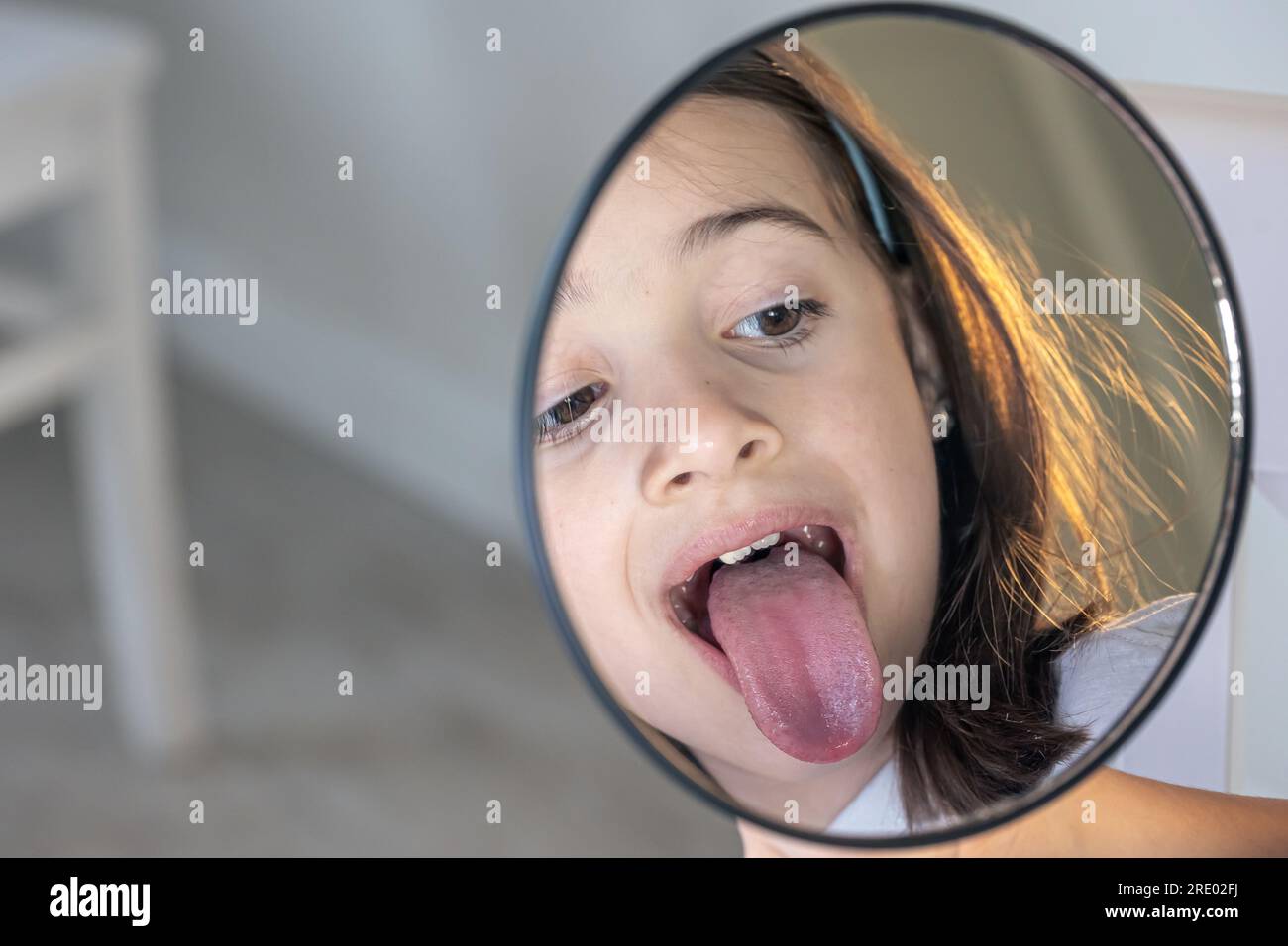 Ein weißes Mädchen mit Zahnspange, das in den Spiegel schaut. Stockfoto