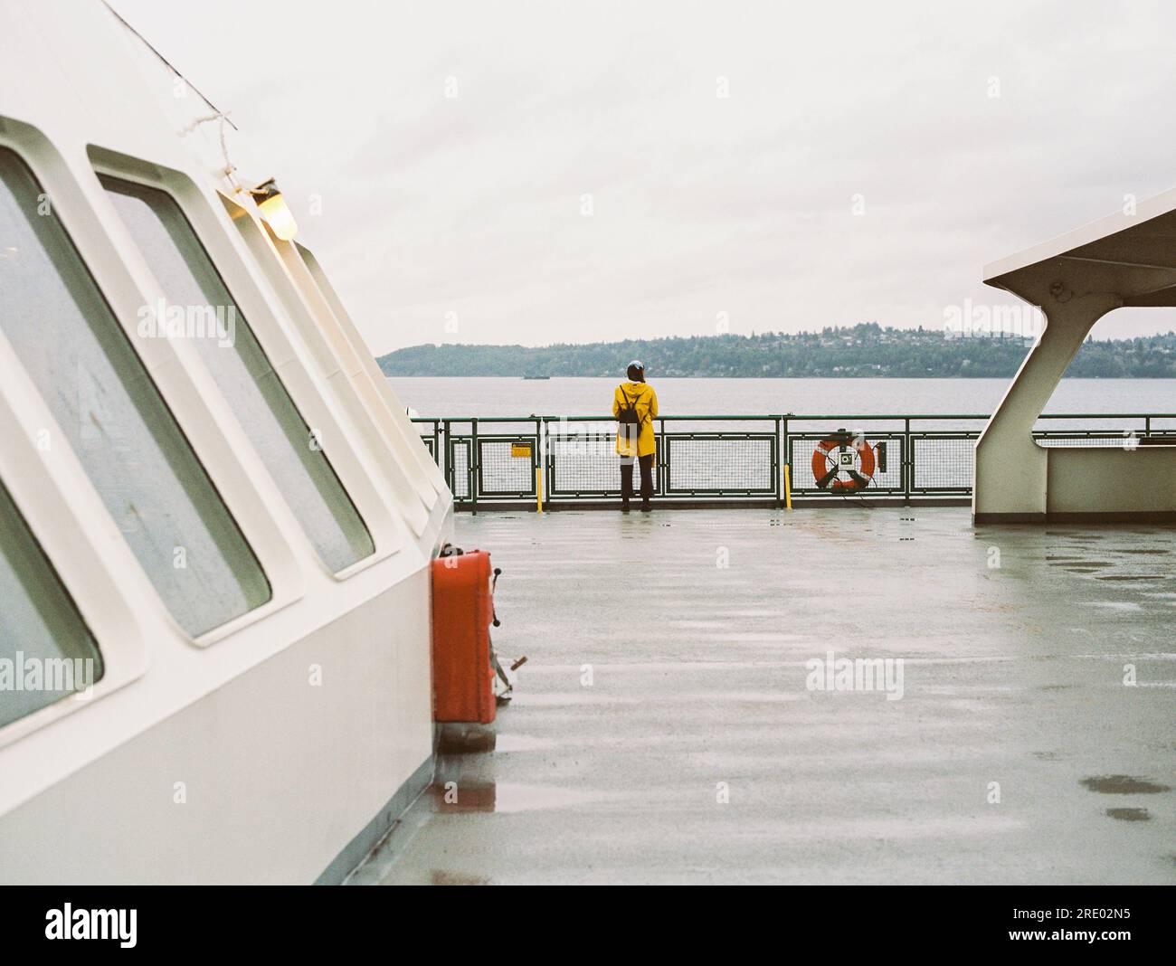 Frau in gelber Regenjacke fährt Fähre im Regen, auf 35mm Film Stockfoto