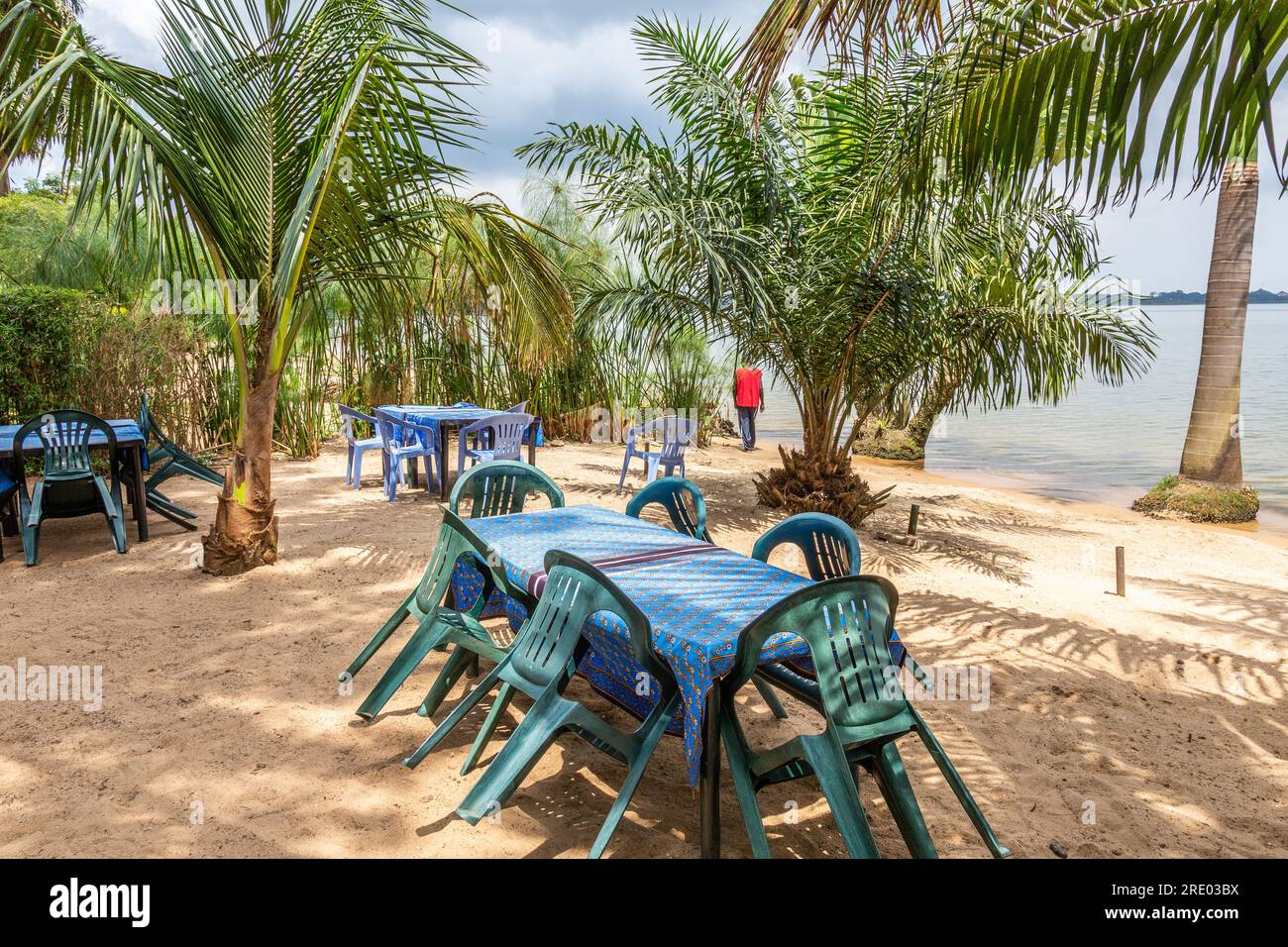 Ein Restaurant mit Tischen und Stühlen wartet am Anderita Beach in Entebbe, Uganda. Palmen am Victoria-See. Stockfoto