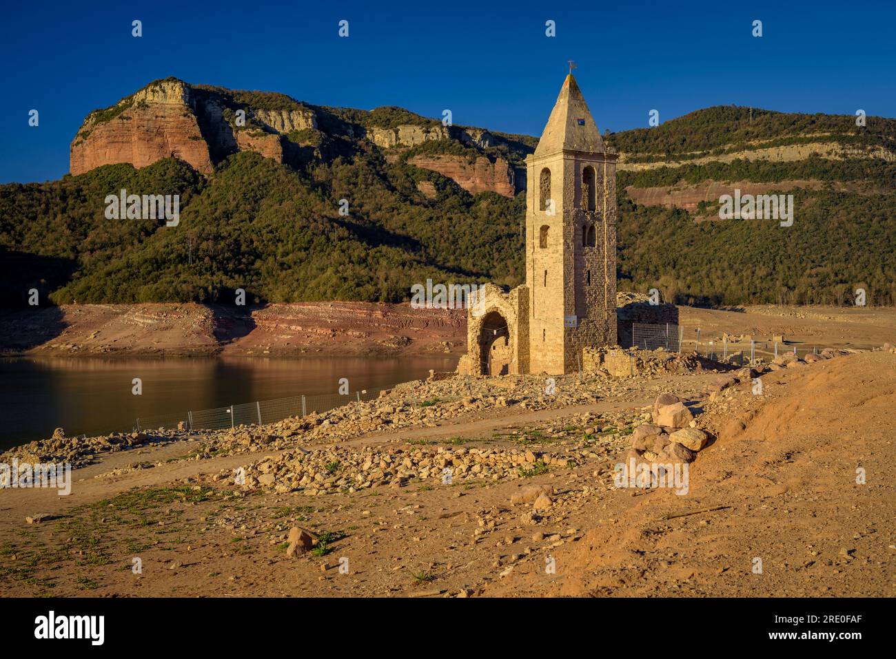 Glockenturm von Sant Romà de Sau bei Sonnenaufgang mit fast leerem Sau-Reservoir während der Dürre 2022-23 (Osona, Barcelona, Katalonien, Spanien) Stockfoto