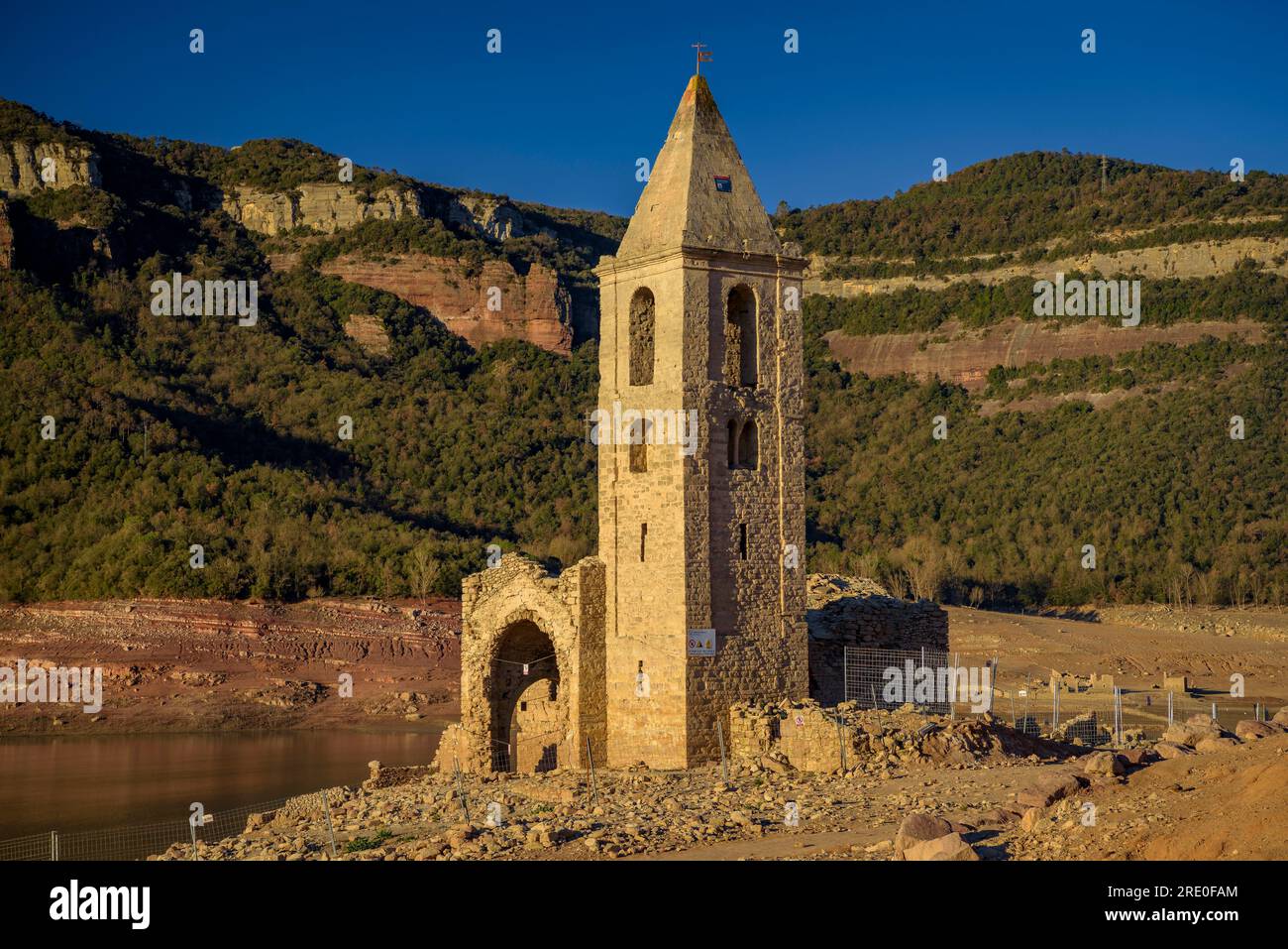 Glockenturm von Sant Romà de Sau bei Sonnenaufgang mit fast leerem Sau-Reservoir während der Dürre 2022-23 (Osona, Barcelona, Katalonien, Spanien) Stockfoto