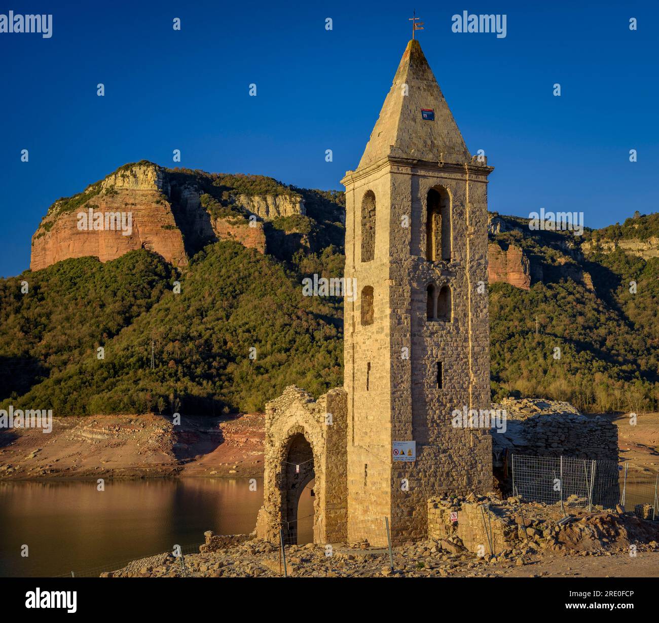 Glockenturm von Sant Romà de Sau bei Sonnenaufgang mit fast leerem Sau-Reservoir während der Dürre 2022-23 (Osona, Barcelona, Katalonien, Spanien) Stockfoto