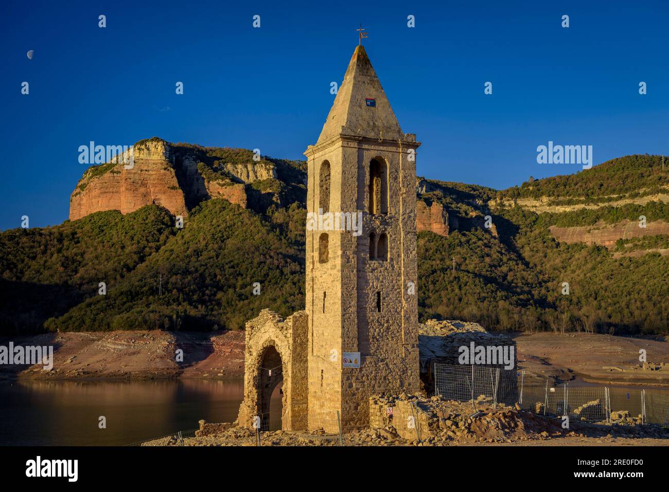Glockenturm von Sant Romà de Sau bei Sonnenaufgang mit fast leerem Sau-Reservoir während der Dürre 2022-23 (Osona, Barcelona, Katalonien, Spanien) Stockfoto