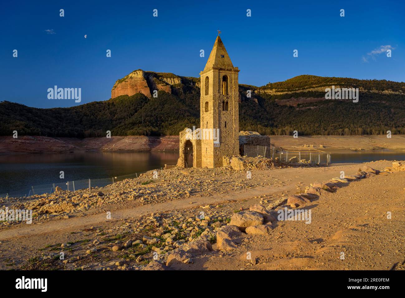 Glockenturm von Sant Romà de Sau bei Sonnenaufgang mit fast leerem Sau-Reservoir während der Dürre 2022-23 (Osona, Barcelona, Katalonien, Spanien) Stockfoto