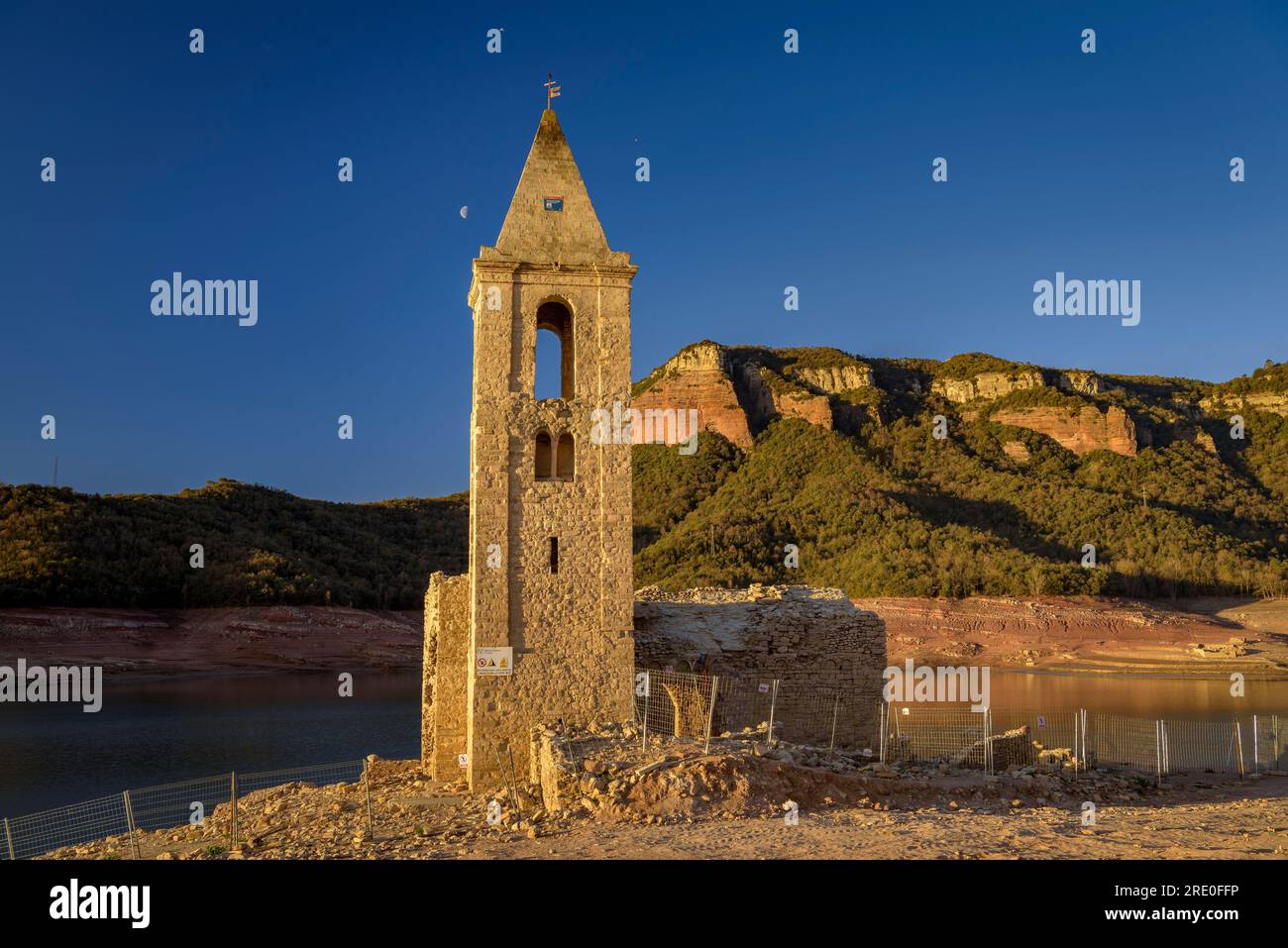 Glockenturm von Sant Romà de Sau bei Sonnenaufgang mit fast leerem Sau-Reservoir während der Dürre 2022-23 (Osona, Barcelona, Katalonien, Spanien) Stockfoto