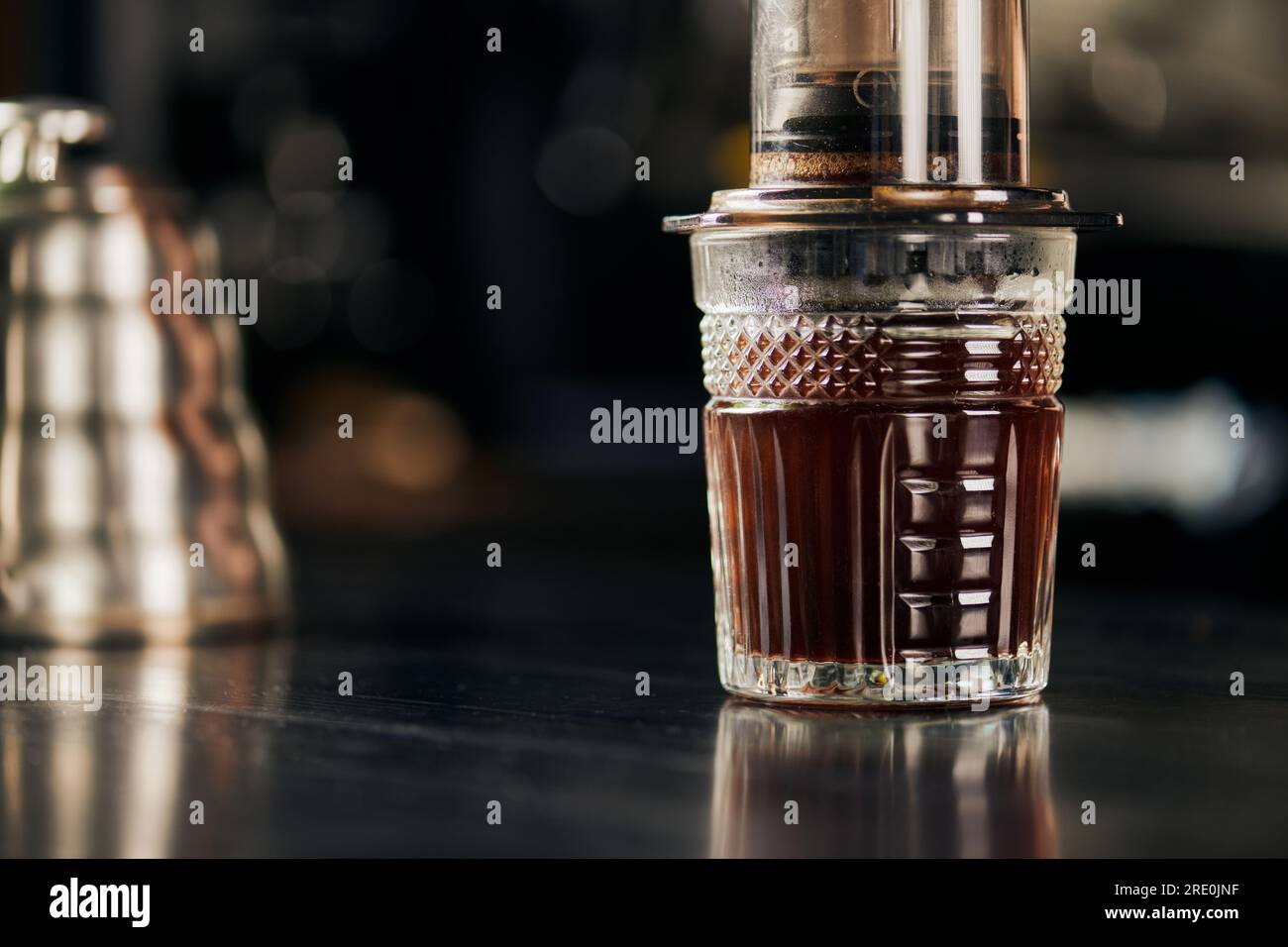 Kristallglas mit aromatischem und frisch gebrühtem Espresso, zubereitet in einer Aero Press-Kaffeemaschine Stockfoto