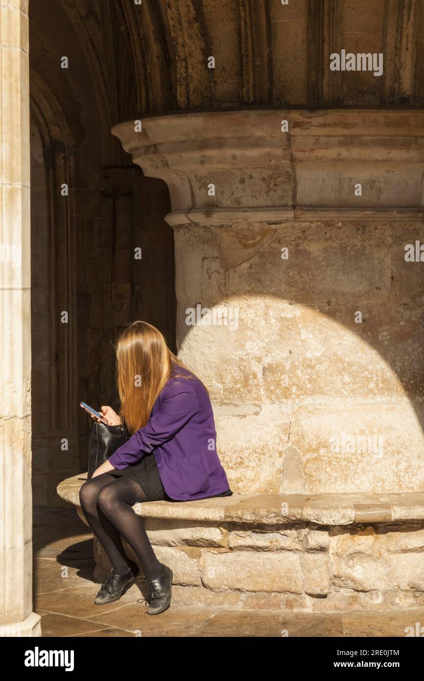 England, Sussex, West Sussex, Chichester, Chichester Market Cross, Schulmädchen sitzt unter dem Marktkreuz mit Handy Stockfoto