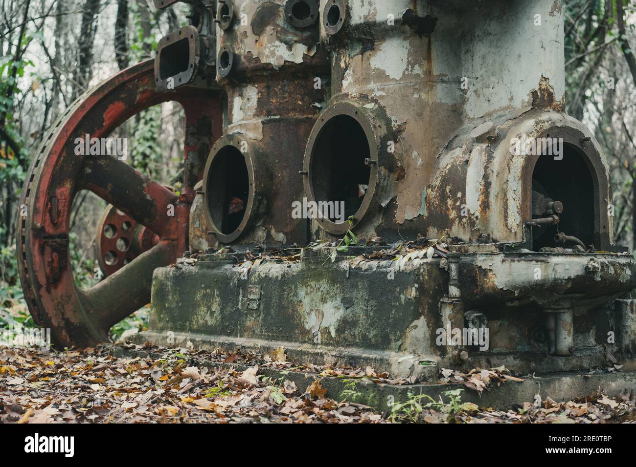 Ein alter rostiger, großer Luftkompressor mit rotem Rad im Wald. Industrielle Geschichtsmaschine. Eisen- und Stahlproduktion. Verlassene Maschinen. Stockfoto
