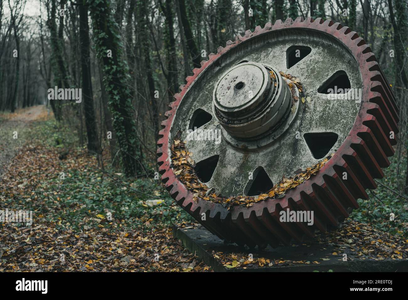 Ein altes, unbenutztes rotes Gerät im Herbst im Wald. Industrielle Geschichtsmaschine. Verlassene Maschinen. Eisen- und Stahlproduktion. Stockfoto