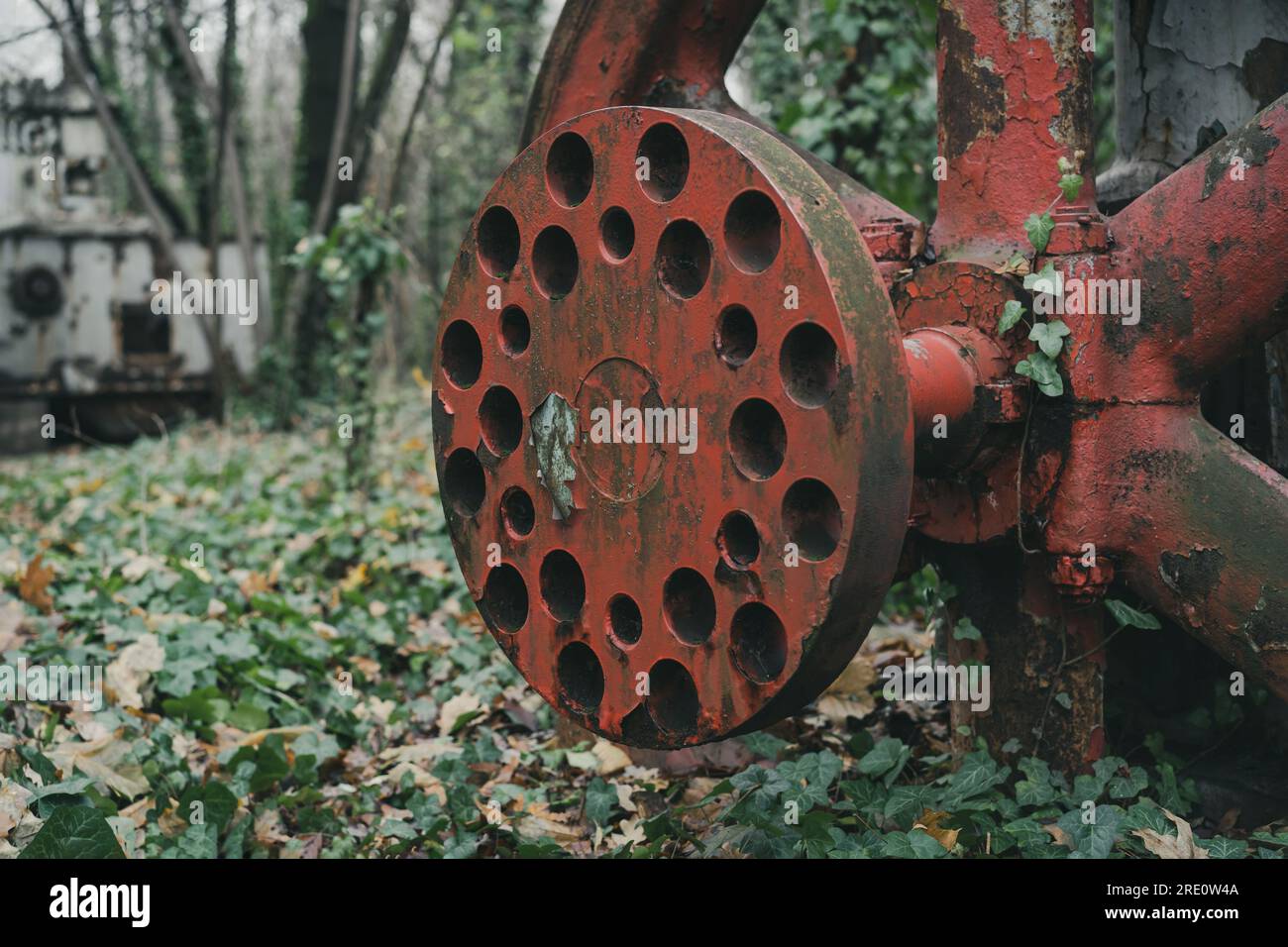 Detail des rostigen roten Rads eines alten unbenutzten Luftkompressors im Wald. Industrielle Geschichtsmaschine. Eisen- und Stahlproduktion. Verlassene Maschine Stockfoto