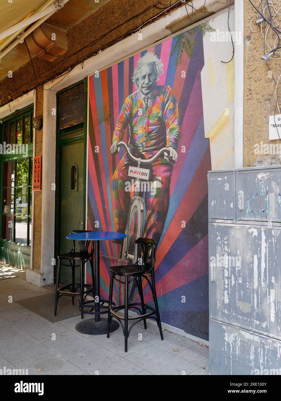 Farbenfrohe Posterillustration von Albert Einstein, der auf einem Fahrrad fährt, vor einem Café in der Stadt Plovdiv, Bulgarien Stockfoto