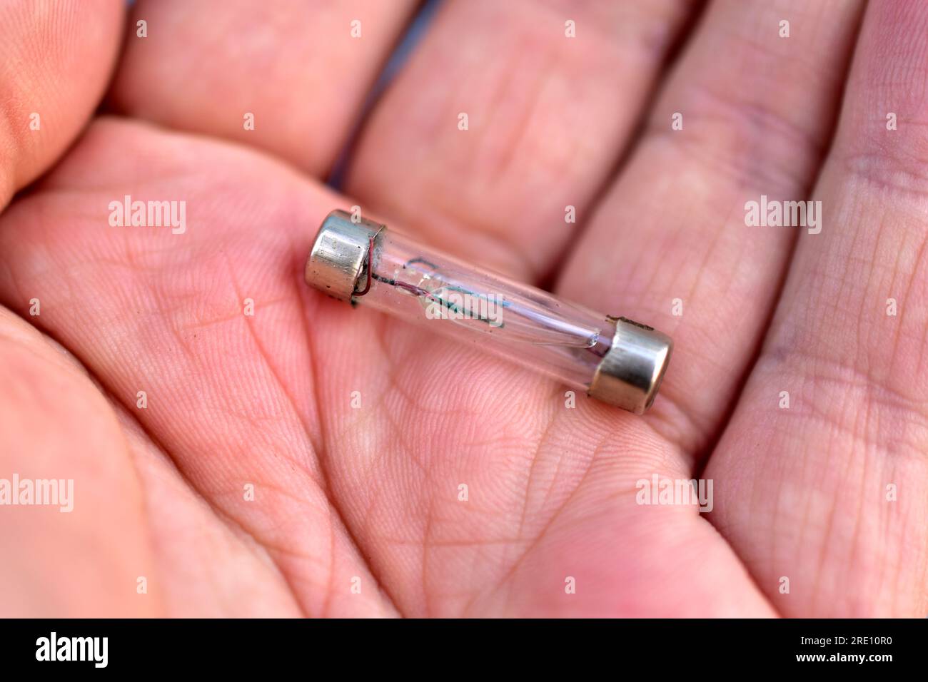 Normale Drahtsicherung in einem Glasgehäuse in der Hand Stockfoto