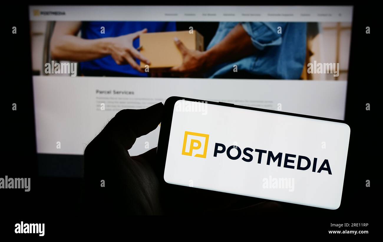 Person, die ein Mobiltelefon mit dem Logo des Medienunternehmens Postmedia Network Canada Corp. Auf dem Bildschirm vor der Webseite hält. Konzentrieren Sie sich auf das Display des Telefons. Stockfoto