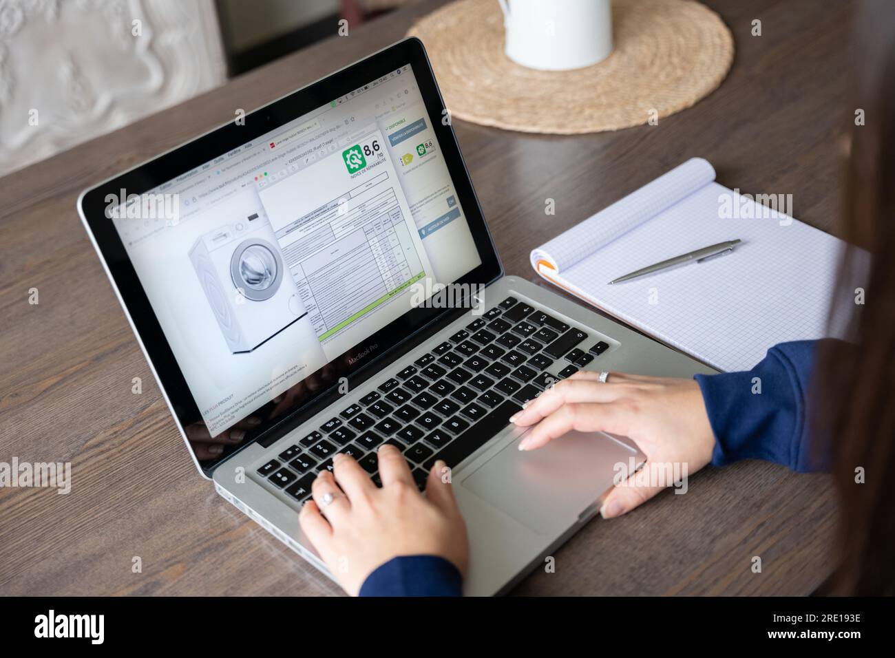 Eine Frau konsultiert das Reparaturetikett einer Waschmaschine in einem Webshop. Die Hersteller müssen auf einer Skala von A E angeben, wie einfach ihre devi-werte sind Stockfoto