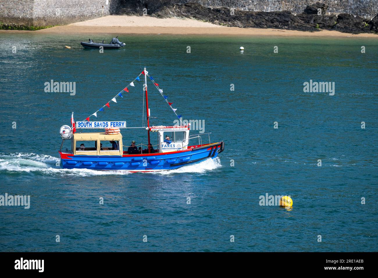 The ferry to South Sands sailing along Salcombe Estuary with East Portlemouth beach visible in the distance, with calm waters and a wake visible. Stockfoto