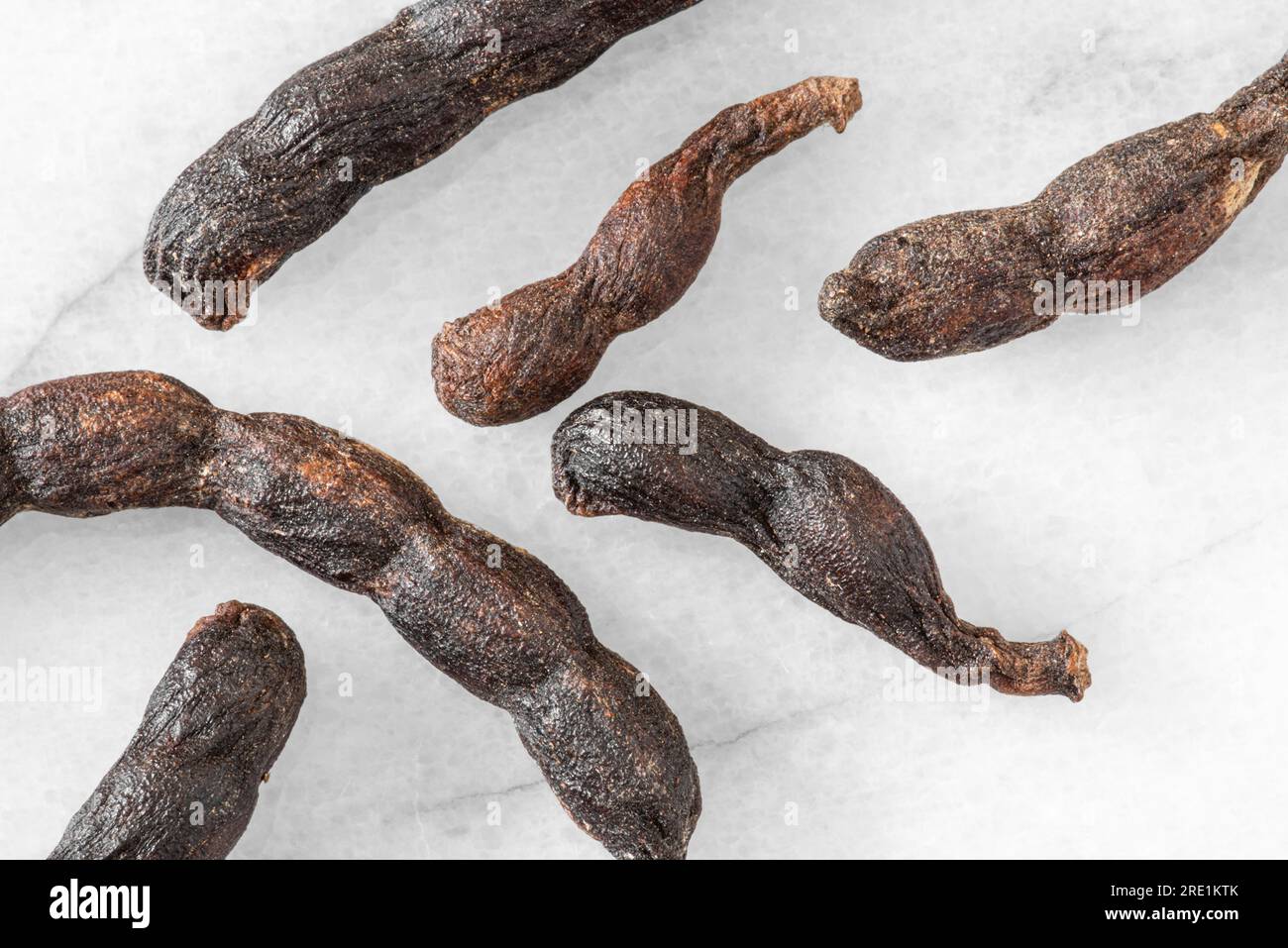 Nahaufnahme von verlängerten afrikanischen schwarzen Paprika-Schoten auf weißem Marmorhintergrund Stockfoto