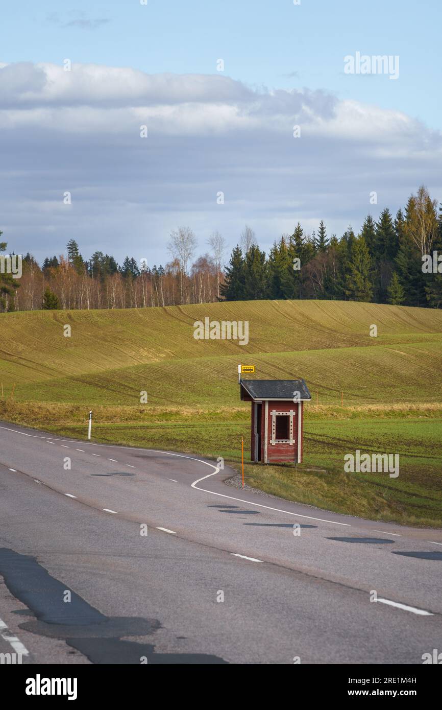 Bushaltestelle in finnischer Landschaft mit rotem Holzschutzdach und grünen Feldern im Hintergrund Stockfoto