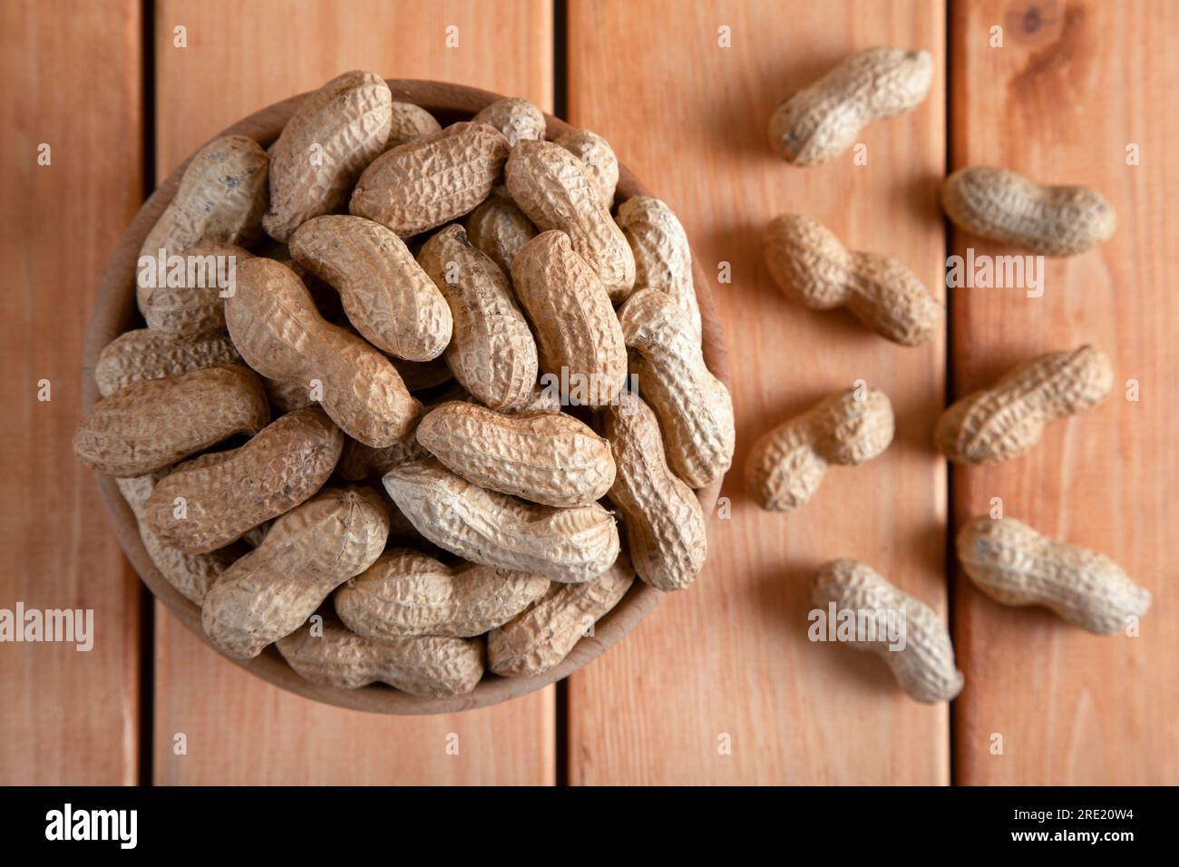 Schüssel voll mit geschälten Erdnüssen auf einem Holztisch Stockfoto