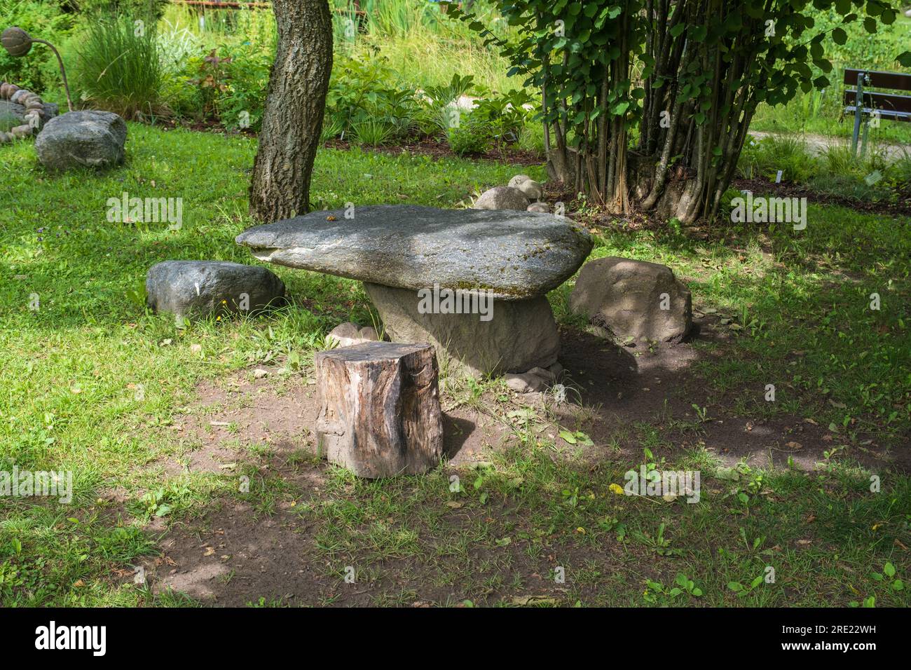 Ein Ruheplatz im Park. Picknickbereich im Garten. Picknicktisch aus Stein mit Bänken auf einem wunderschönen Rasen in ruhiger Lage. Ein schöner Picknickplatz Stockfoto