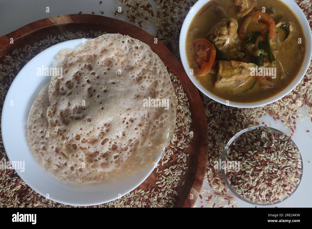 Rajamudi-Reis-Appam serviert mit kerala-Hühnchen-Curry. Reiscrepes oder Pfannkuchen mit fermentiertem Ramamudi-Reisteig und Kokosmilch. Eine Version von Stockfoto