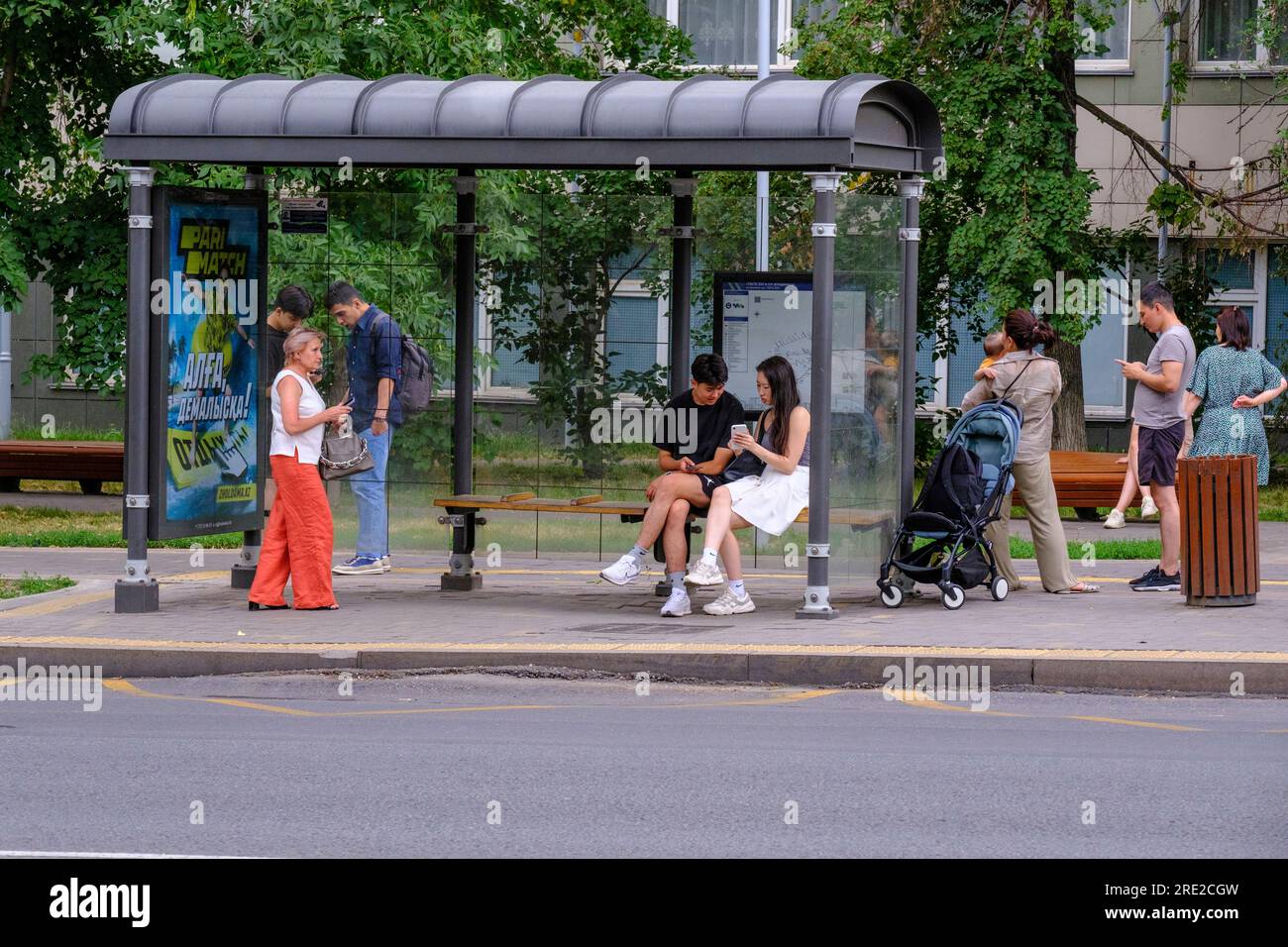 Kasachstan, Almaty. Straßenszene: Passagiere, die an der Bushaltestelle auf den Bus warten. Stockfoto