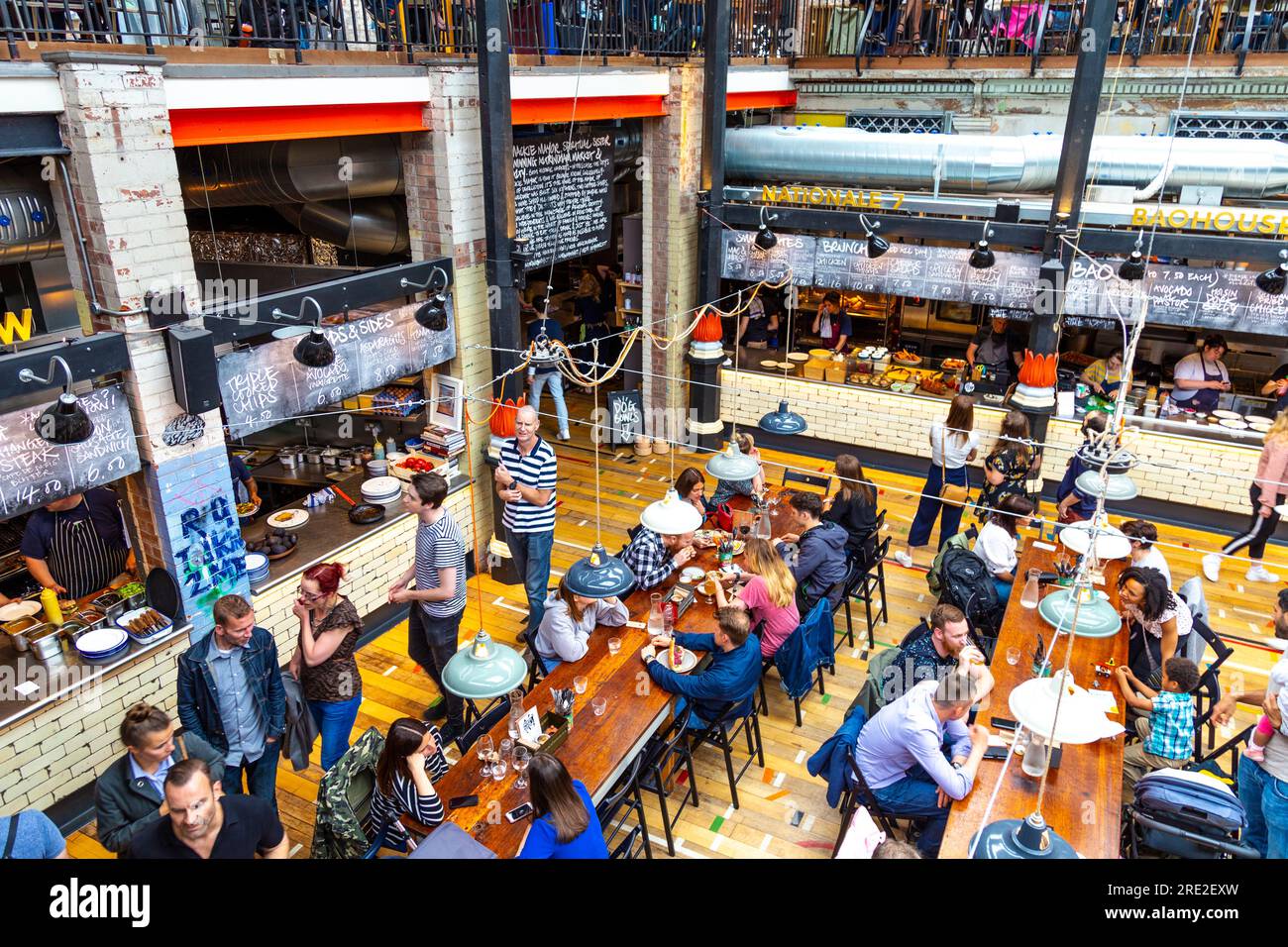 Die Menschen essen in einem Food Court, Interieur des Mackie Bürgermeister in einem ehemaligen Fleischmarkt Gebäude in Manchester, Großbritannien Stockfoto