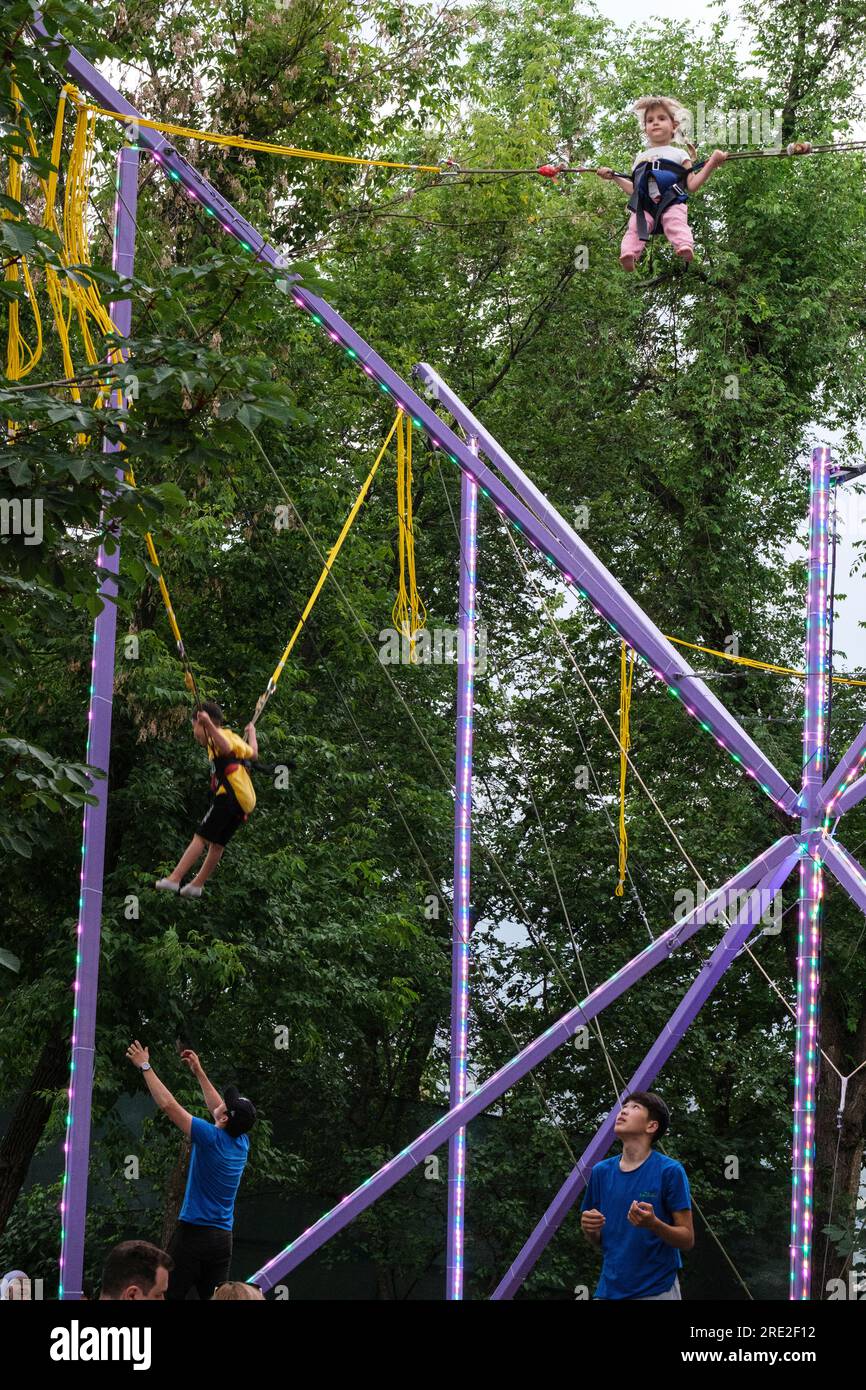 Kasachstan, Almaty. Kok-Tobe-Park. Junge Jungen und Mädchen schweben in der Luft an elastischen Seilen. Stockfoto