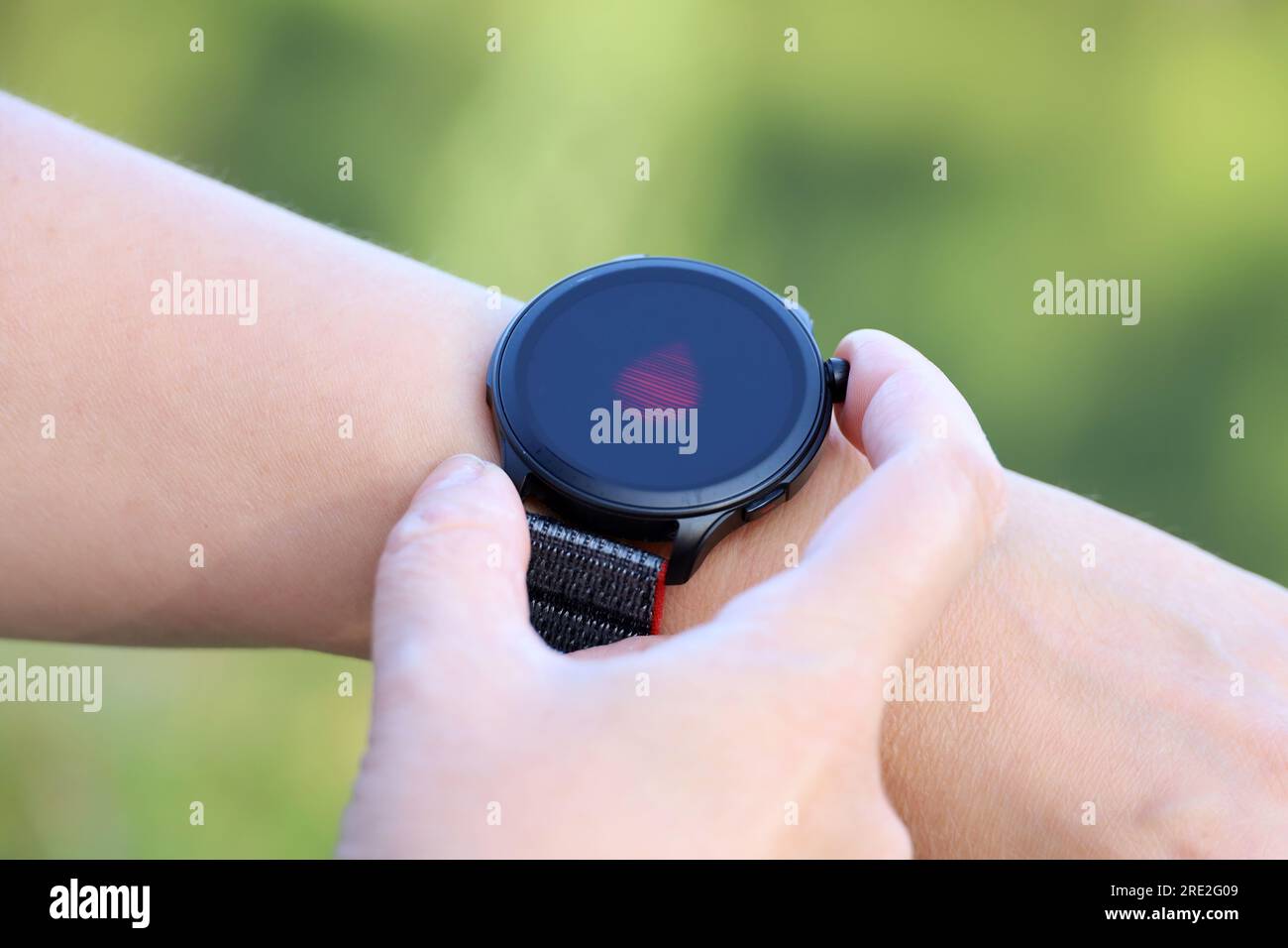 Intelligente Uhr an der weiblichen Hand, die den Sauerstoffgehalt im Blut misst. Rundes Display mit App zur Gesundheitsüberwachung Stockfoto