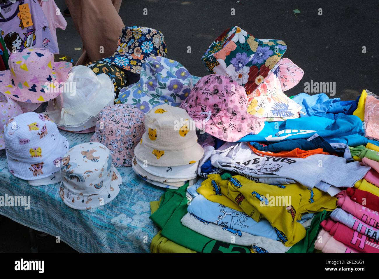 Kasachstan, Almaty. Kindermützen und T-Shirts werden vom Straßenverkäufer in der Nähe des Green Bazaar verkauft. Stockfoto