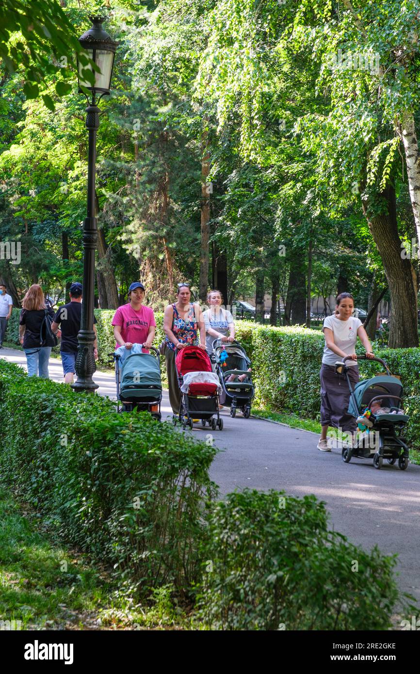 Kasachstan, Almaty. Eltern schieben Kinderwagen im Park der 28 Panfilov-Wachmänner. Stockfoto