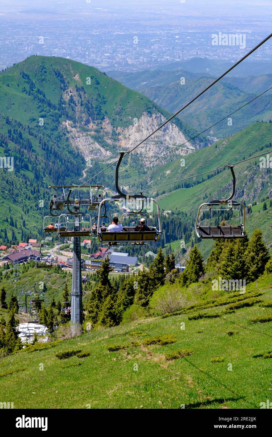 Kasachstan, Almaty. Abfahrt mit dem Shymbulak Standseillift vom Skigebiet. Almaty City im Hintergrund. Stockfoto