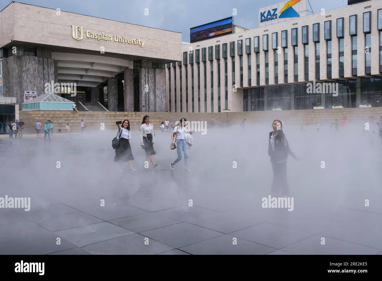 Kasachstan, Almaty. Studenten gehen durch den „Fog Fountain“ vor dem Eingang zur Kaspischen Universität. Stockfoto