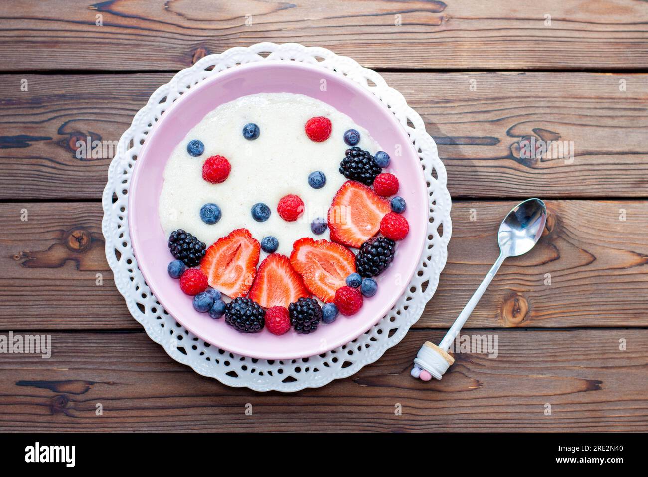 Griechische Joghurtschüssel mit frischen Beeren, Erdbeeren, Himbeeren, Heidelbeeren auf natürlichem Holzhintergrund, Draufsicht Stockfoto